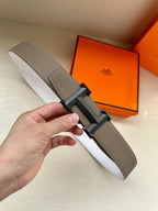 Hermes belt in dark taupe leather with black-gray reversible buckle, shown laid out