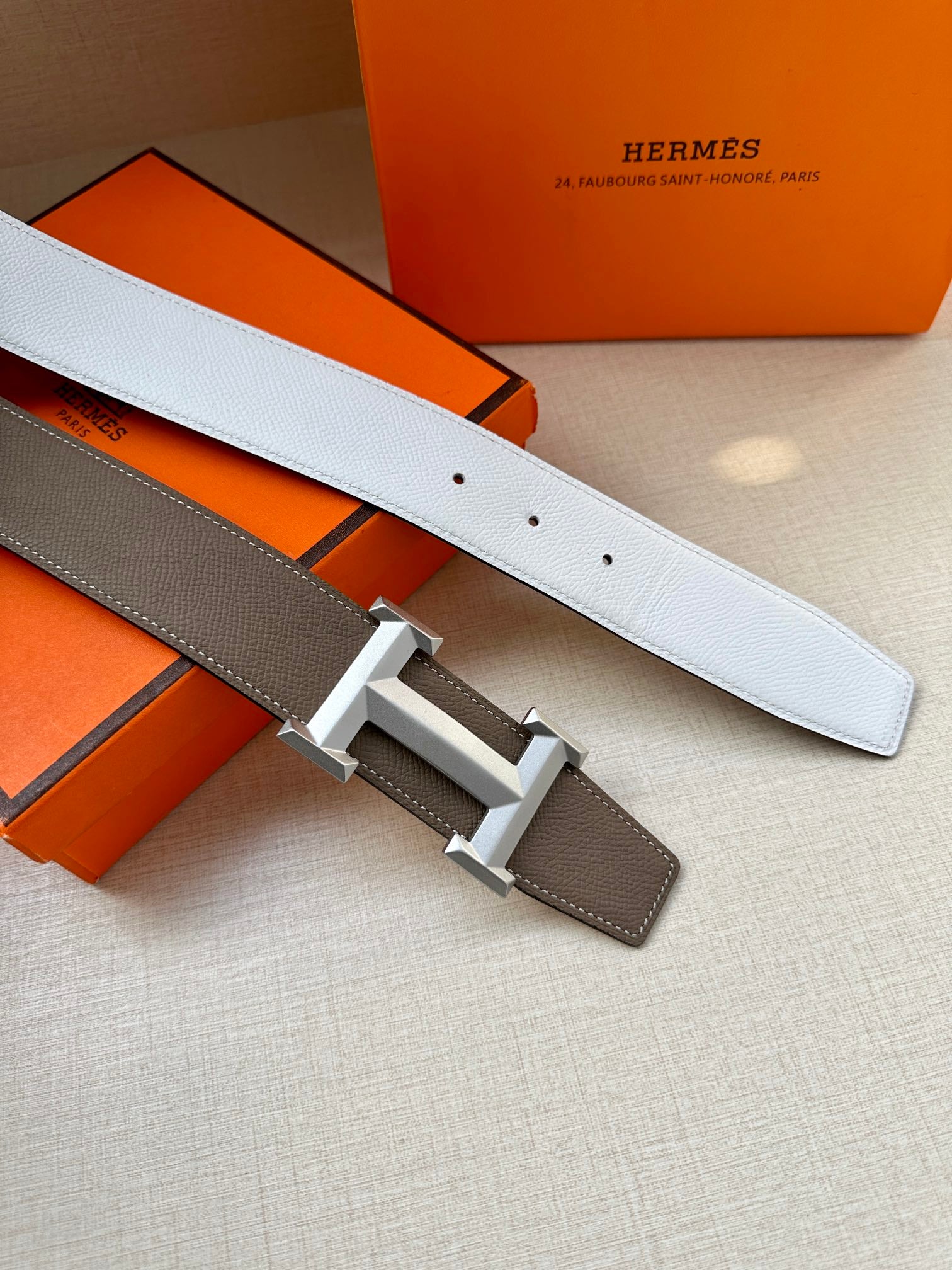 Hermes belt detail: dark taupe strap with black-gray buckle and white belt underside