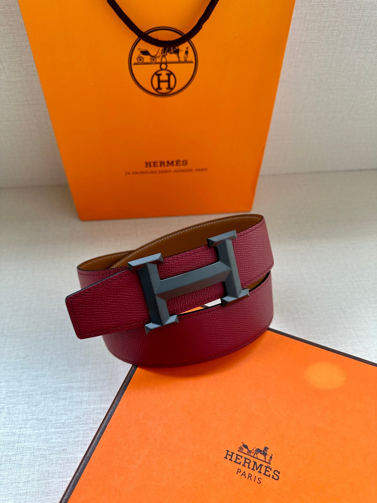 Hermes belt with burgundy leather strap, silver-tone buckle, and tan underside