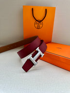 Hermes belt with burgundy strap, silver-tone buckle, and tan inner lining