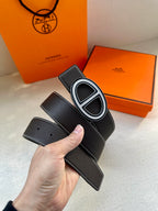 Hermes belt with dark leather strap and double H buckle, loose end visible