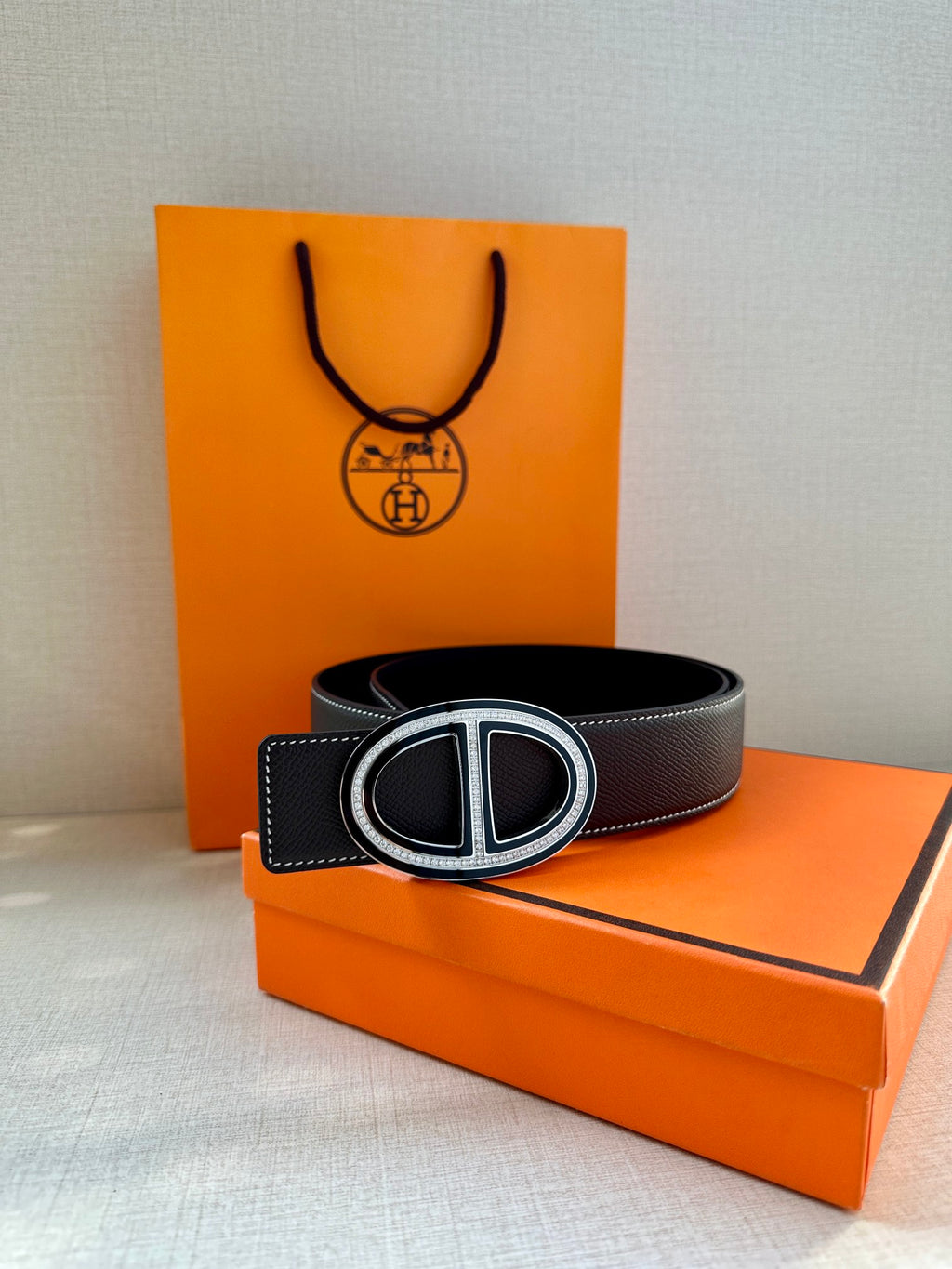 Hermes belt with dark leather strap and double H buckle, laid flat for viewing