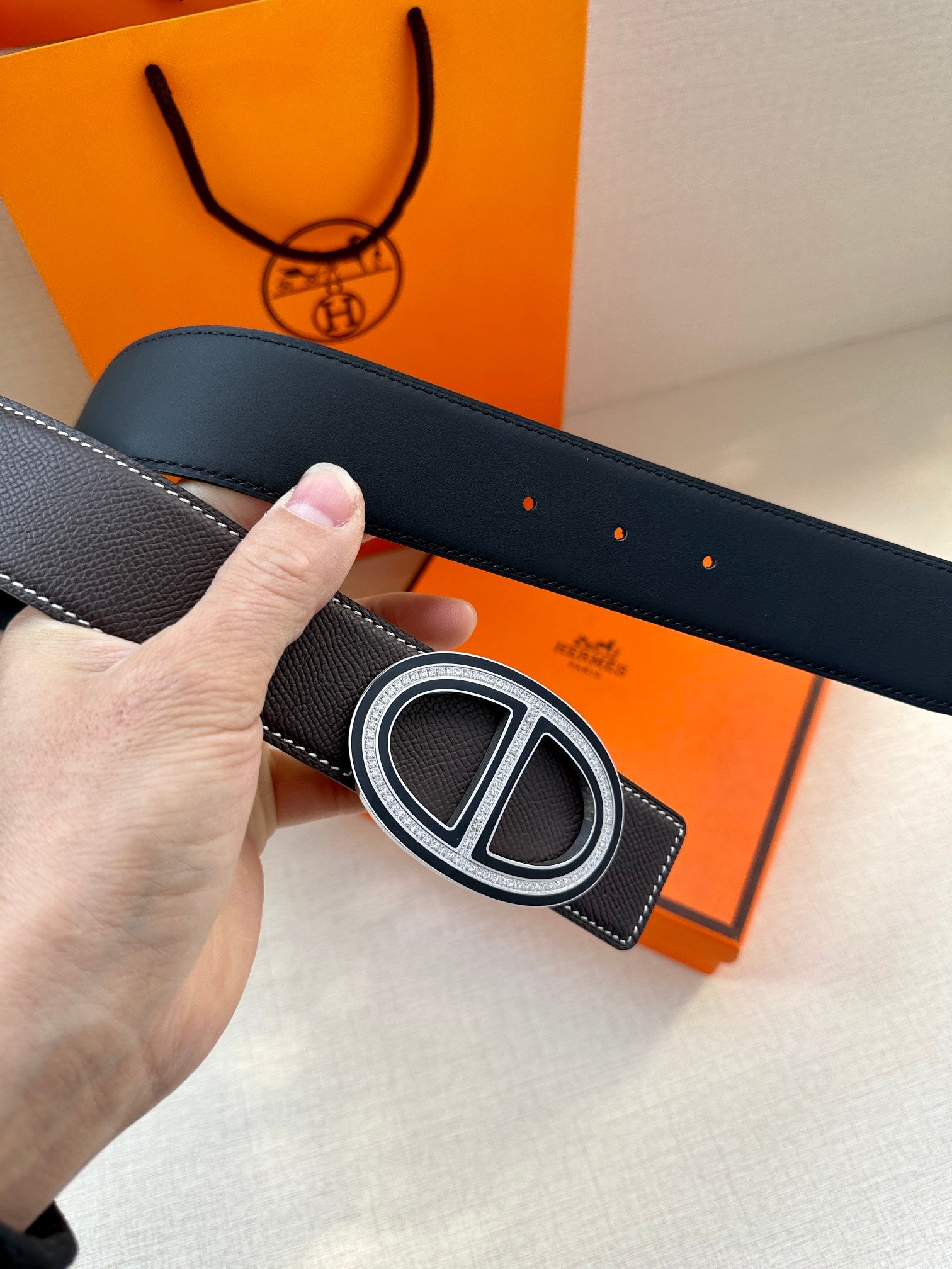 Hermes belt close-up of double H buckle on dark leather strap