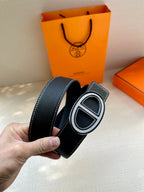 Dark leather belt with oval H buckle, side angle showing strap edge