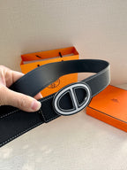 Dark leather belt with oval H buckle, belt interior and strap edge visible