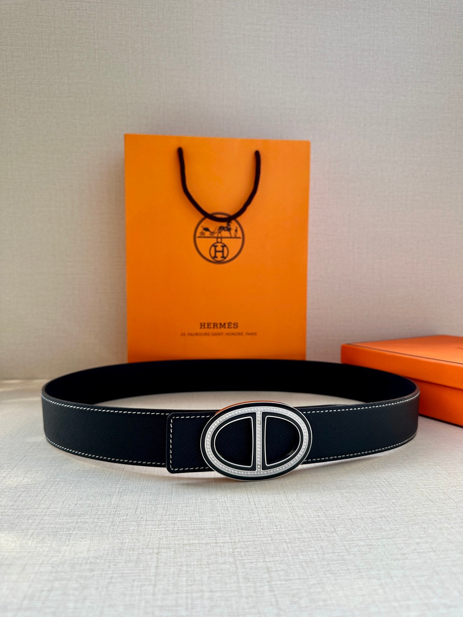 Dark leather belt with oval buckle, front view on display