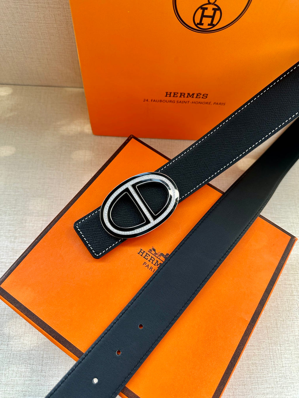 Dark leather belt with oval H buckle and stitched keeper detail