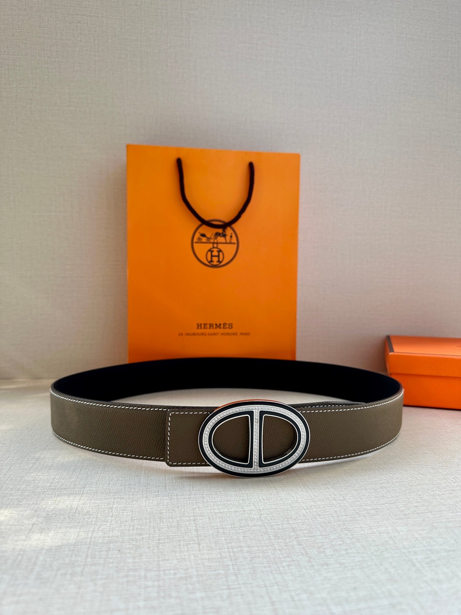 Taupe leather belt with silver-tone oval buckle, laid flat