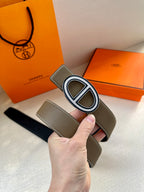 Taupe leather belt with silver-tone oval buckle and visible stitching