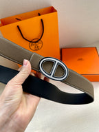 Taupe leather belt with silver-tone oval buckle, black lining showing