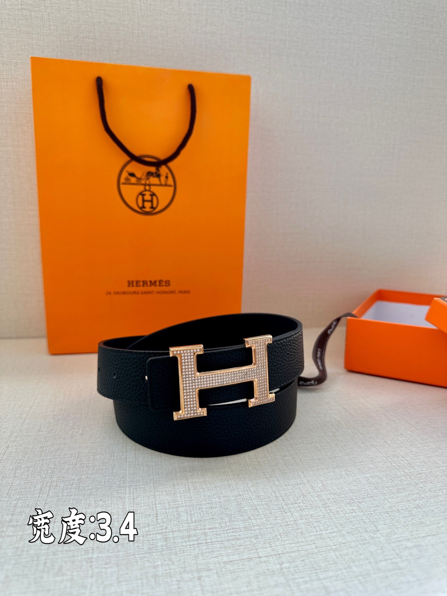 Dark Hermes belt with silver studded H buckle, laid in a loop