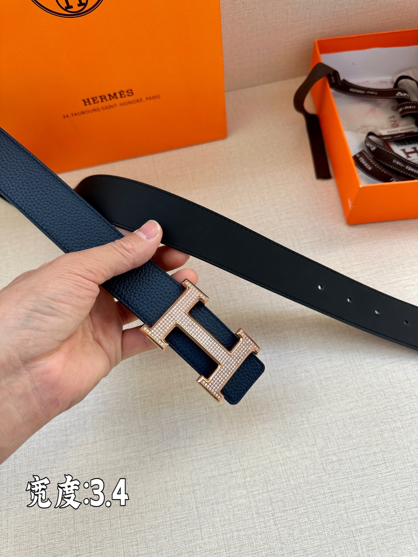Leather belt, dark blue, silver-tone H buckle close-up with strap end