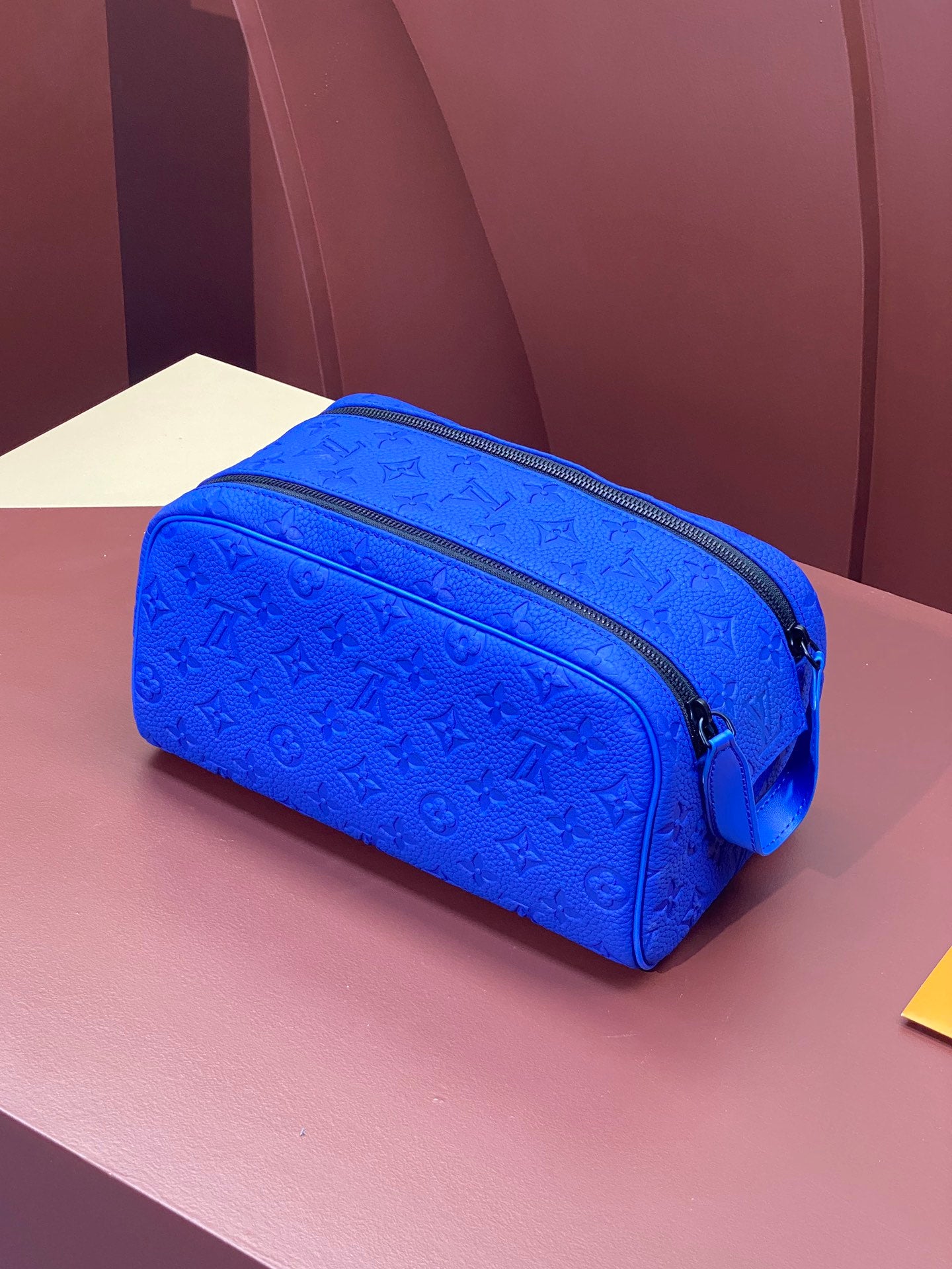 Blue embossed Louis Vuitton zip pouch bag with black zipper trim and monogram texture