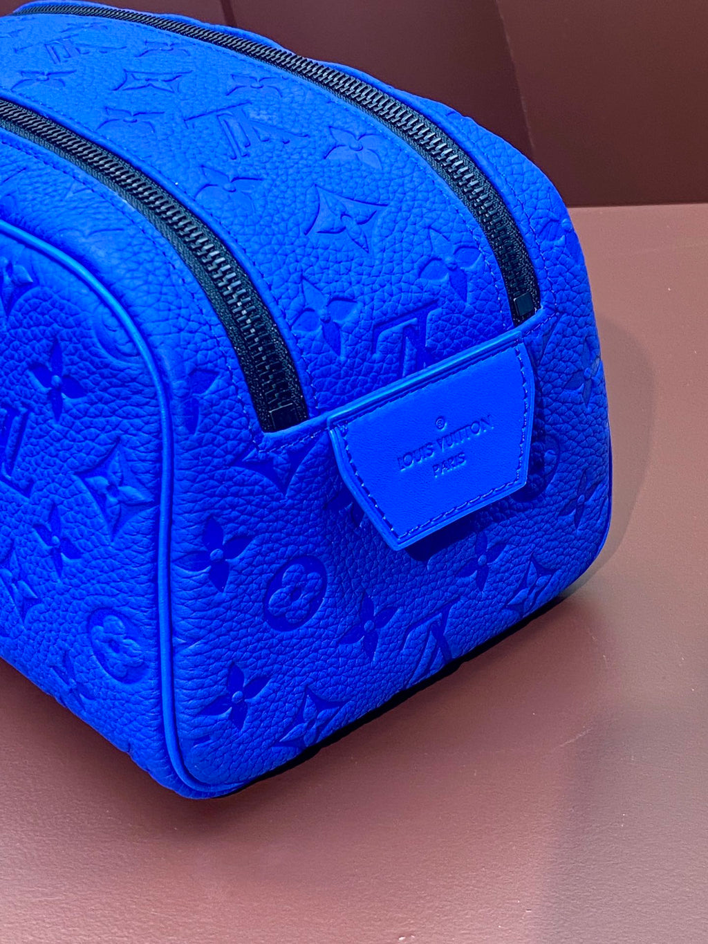 Blue embossed Louis Vuitton zip pouch bag with front patch logo and black zipper edge