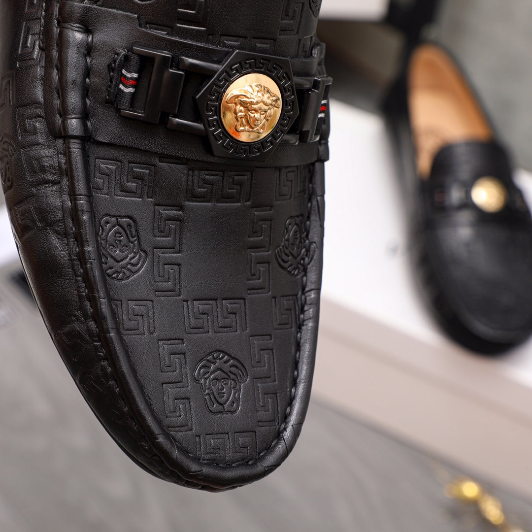 Black leather loafer upper close-up with gold Medusa buckle and embossed motif