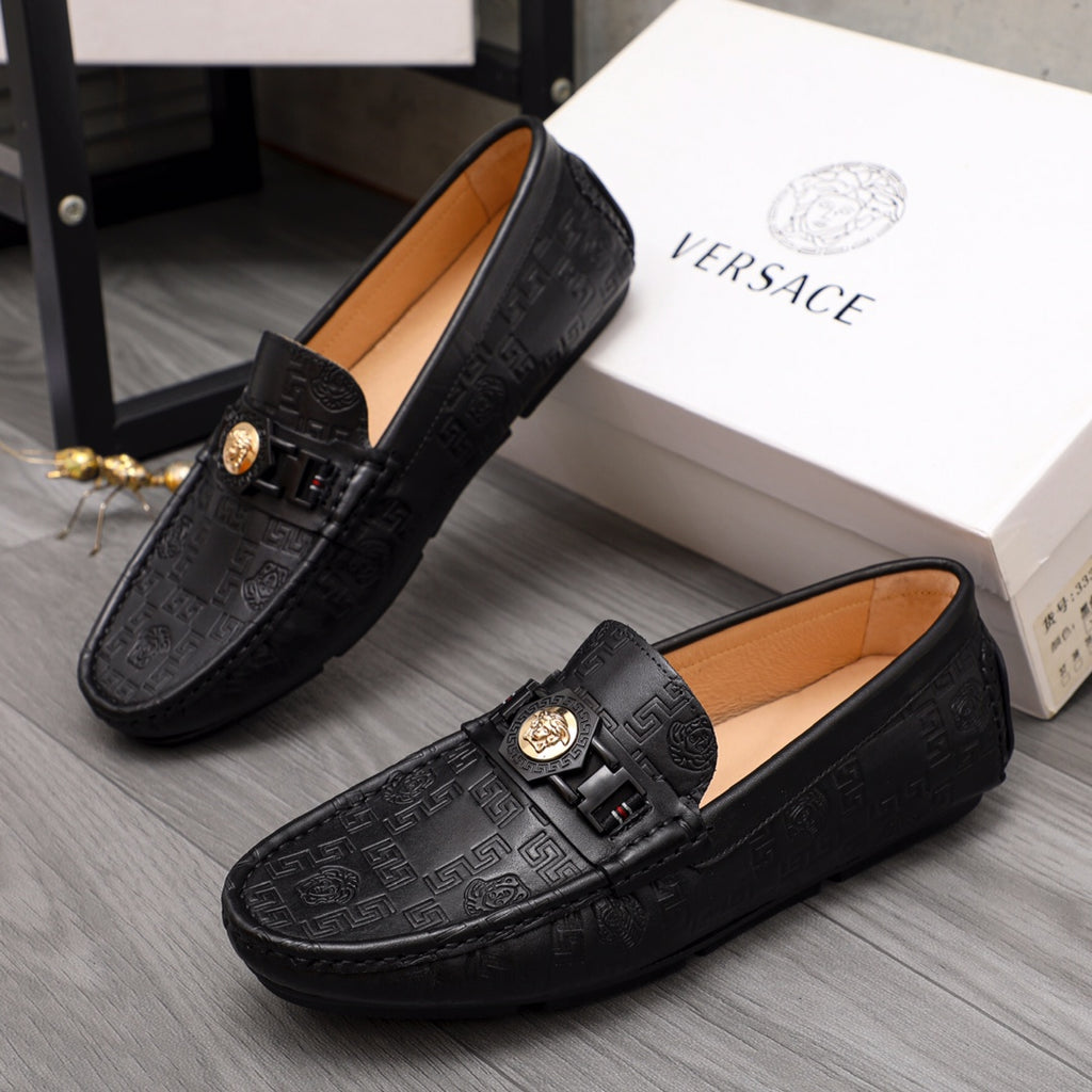 Pair of black leather Versace loafers with gold buckle strap and embossed pattern