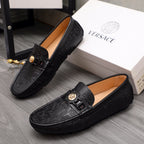 Pair of black leather Versace loafers with gold buckle strap and embossed pattern