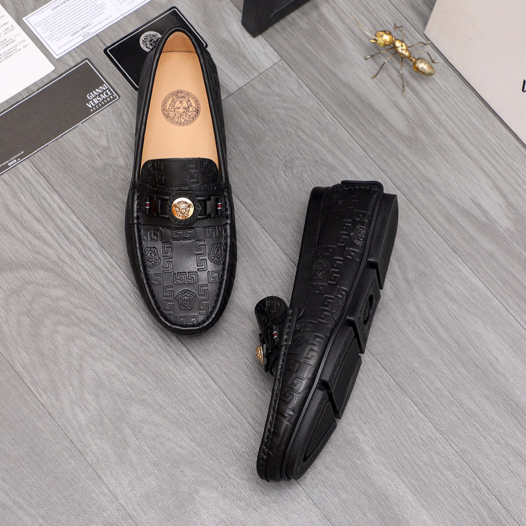 Black leather loafer pair, front view, gold buckle and embossed logo panel