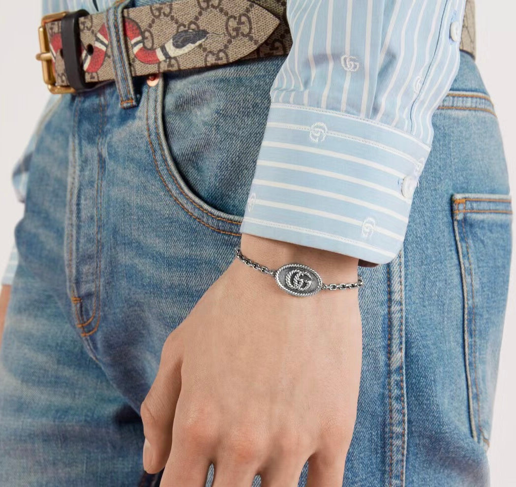 Gucci bracelet on wrist, oval logo charm with silver-tone chain