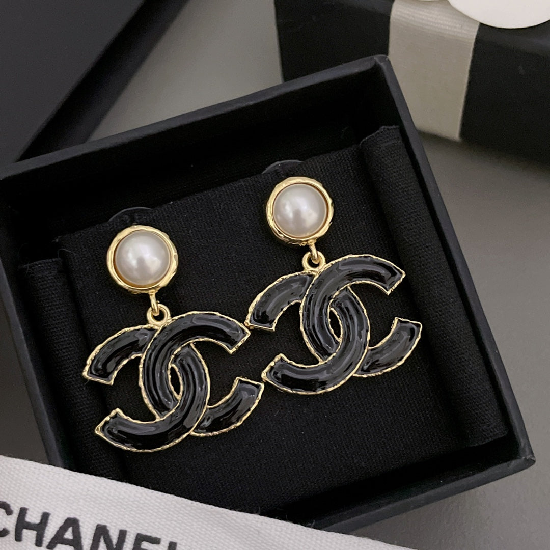 Chanel-style drop earrings with black enamel CC design and round pearl stud tops