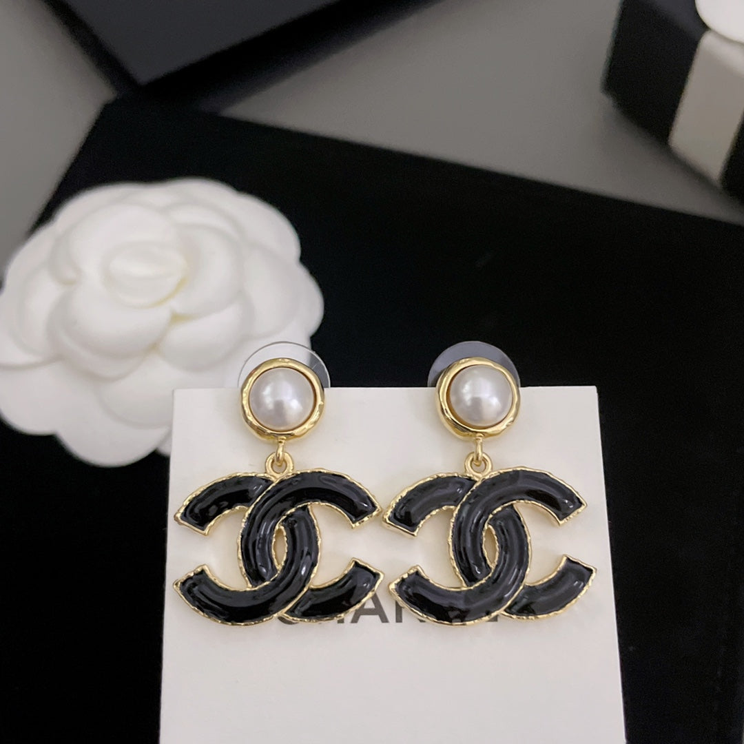 Close-up: Chanel-style earrings with black enamel CC drops and round pearl stud tops