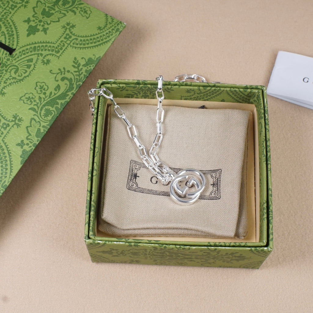 Silver-tone chain necklace with round interlocking GG pendant on beige insert