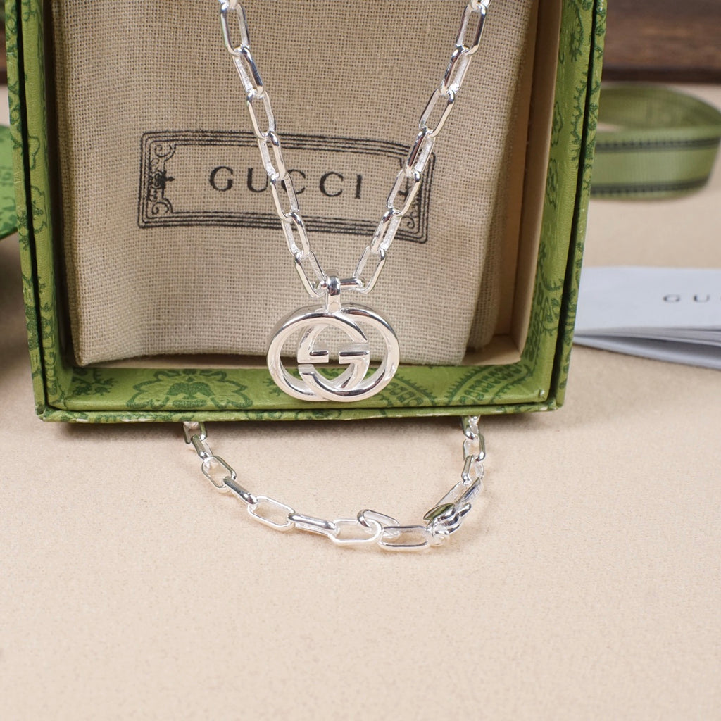 Silver-tone chain necklace with large round interlocking GG pendant on beige pouch
