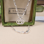 Silver-tone chain necklace with large round interlocking GG pendant on beige pouch