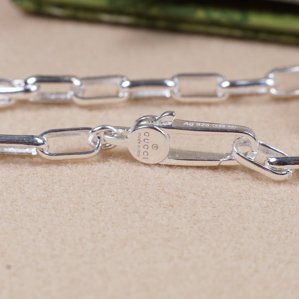 Silver-tone necklace chain links with small engraved metal tag