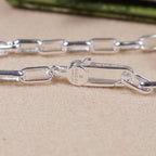 Silver-tone necklace chain links with small engraved metal tag