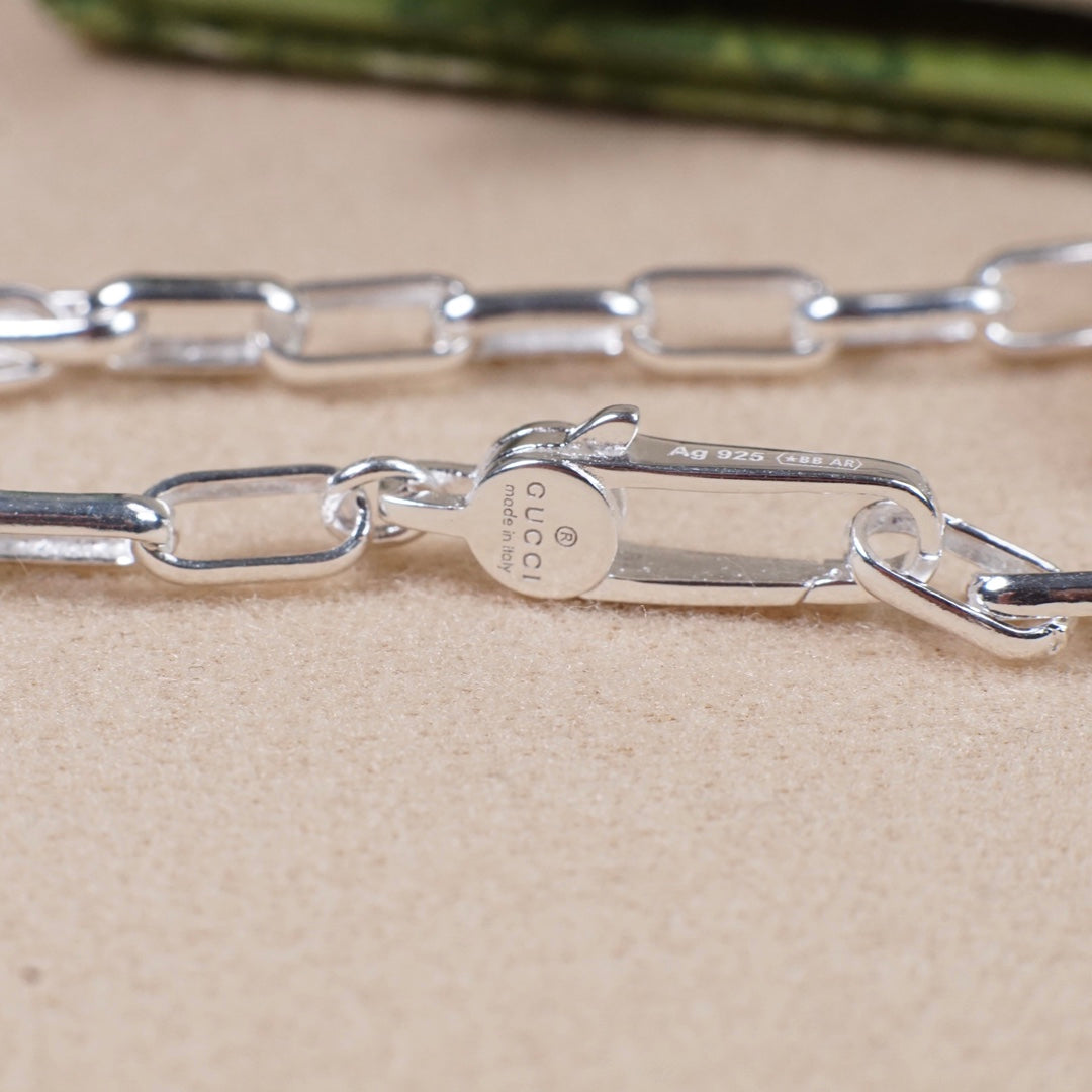 Silver-tone necklace chain links with small engraved metal tag