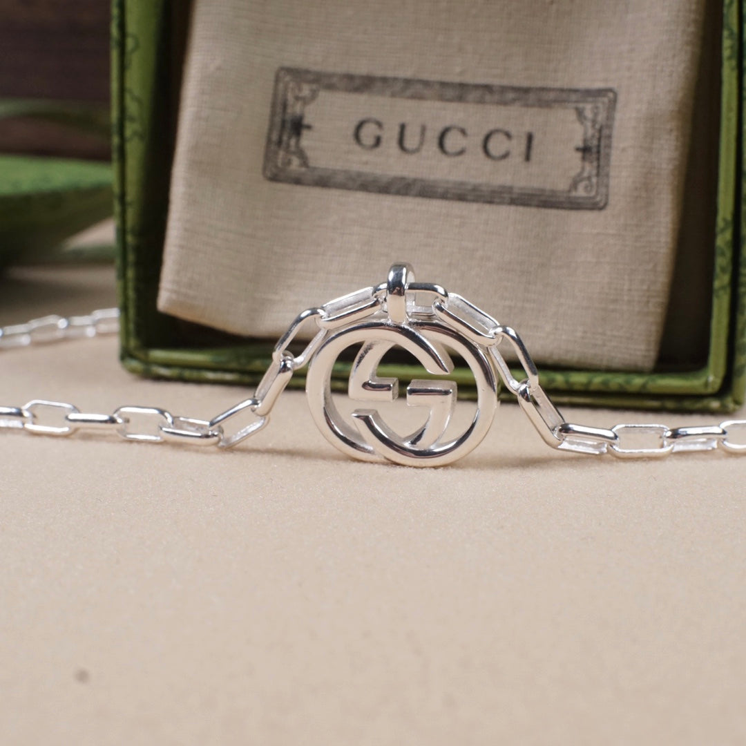 Silver-tone interlocking GG pendant with connected chain links and clasp