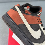 Black and white low-top sneaker with orange-brown suede panel and white strap detail