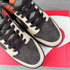 Two low-top sneakers with black laces, white swoosh, and speckled black suede panels