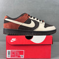 Black, white, and orange low-top sneakers with swoosh and black laces