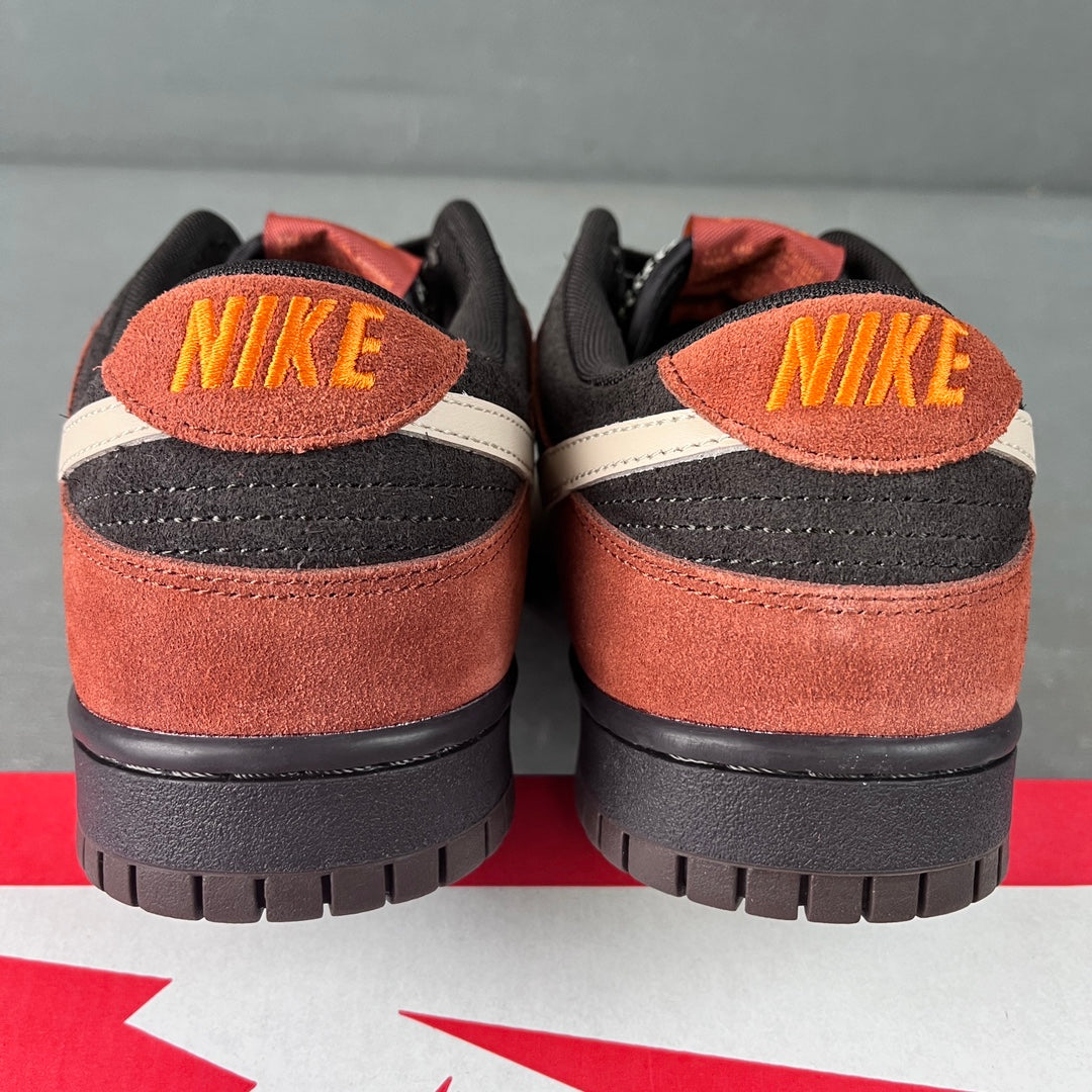 Heel view of black and orange-brown suede low-top sneakers with yellow-orange NIKE logo