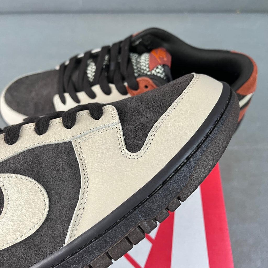 Close-up of black and white low-top sneaker with orange inner lining and black laces
