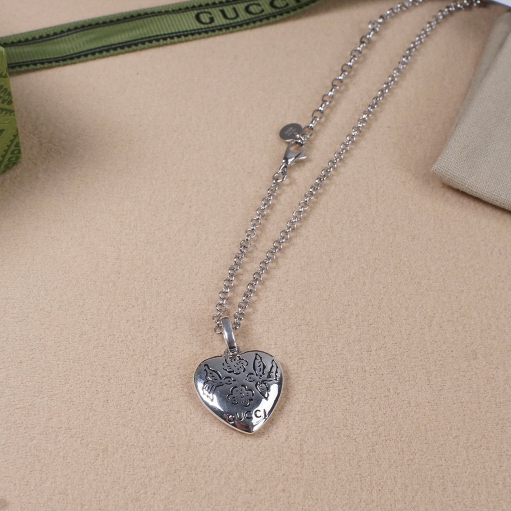 Silver heart pendant necklace with floral engraving and Gucci logo on chain
