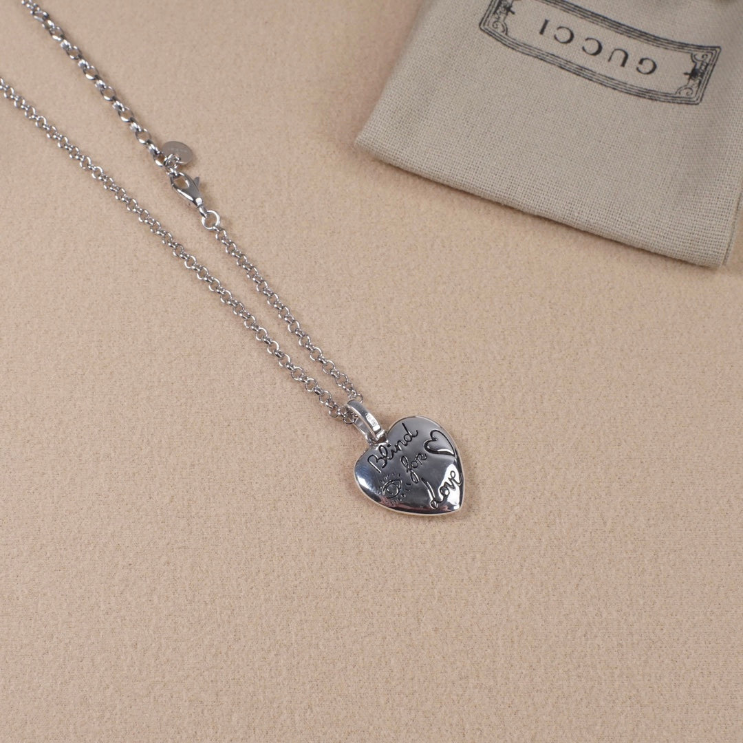 Silver heart pendant necklace with face engraving and Gucci logo on chain