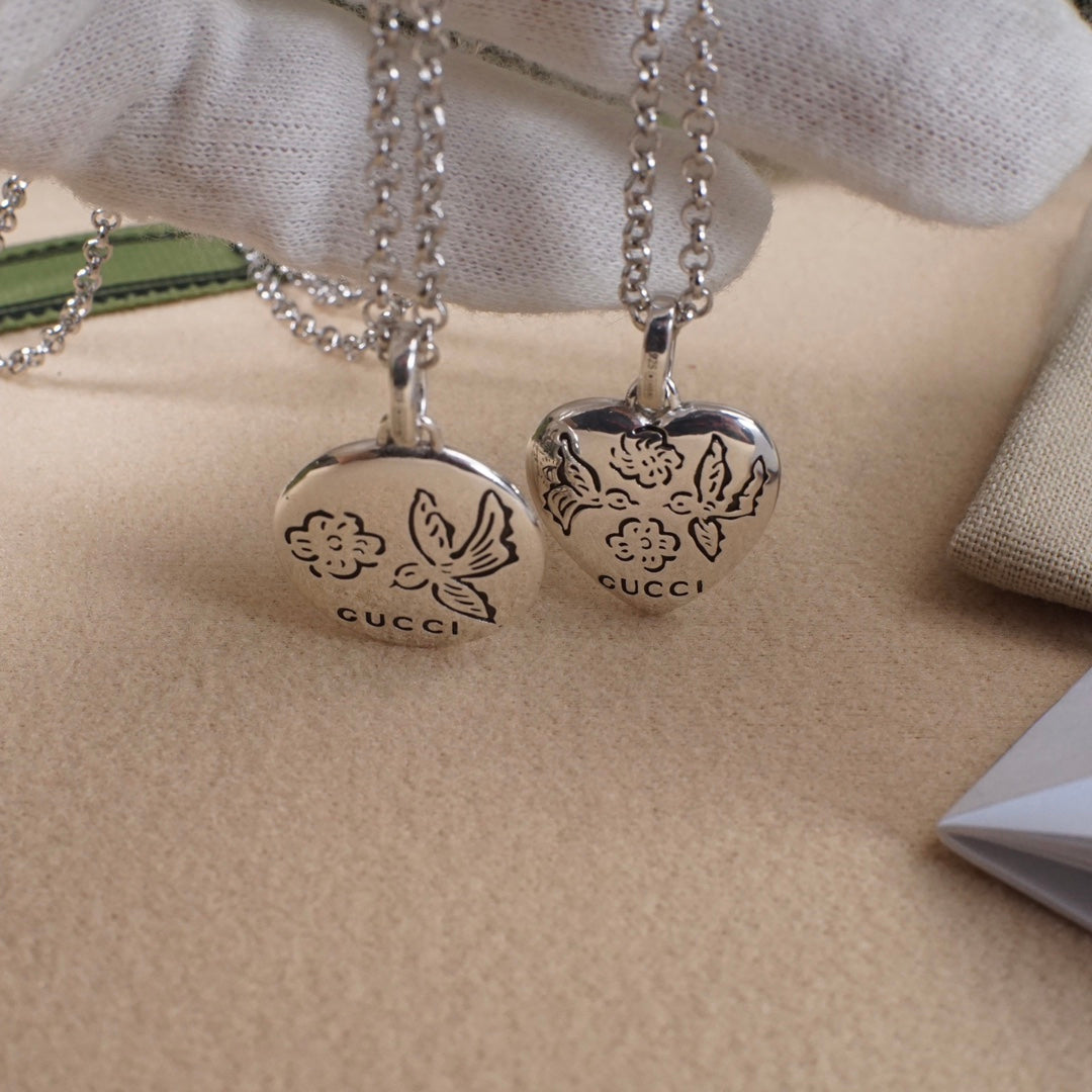 Pair of silver heart pendant necklaces with floral engraving and Gucci logo