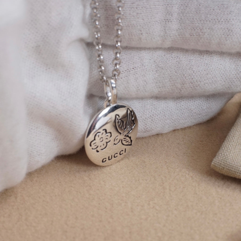 Silver heart pendant necklace with rose-like engraving and Gucci logo