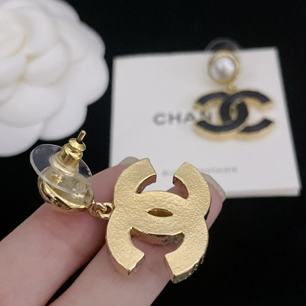 Chanel-style pendant earrings with pearl studs, gold-tone emblem, and pink details