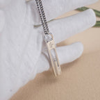 Gucci necklace pendant held in a hand, silver-tone bar with logo