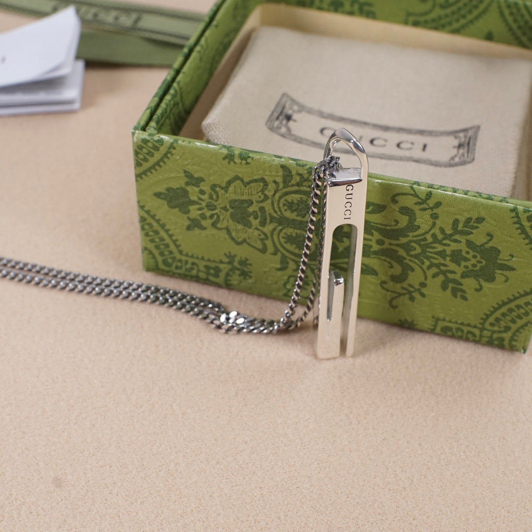 Gucci necklace pendant with silver-tone bar and logo in a green gift box