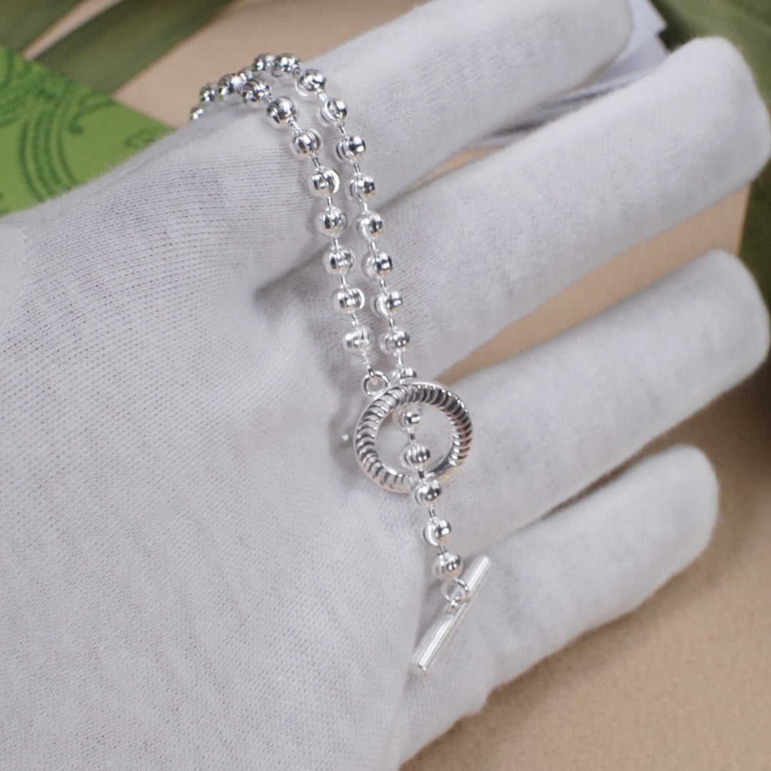 Silver-tone beaded bracelet with circular pendant and slim bar charm
