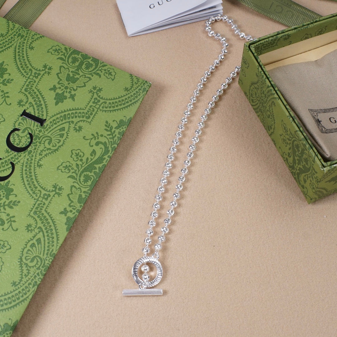 Silver-tone long necklace with circular letter pendant and slim bar charm