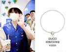 Silver bead necklace with circular pendant worn on a person