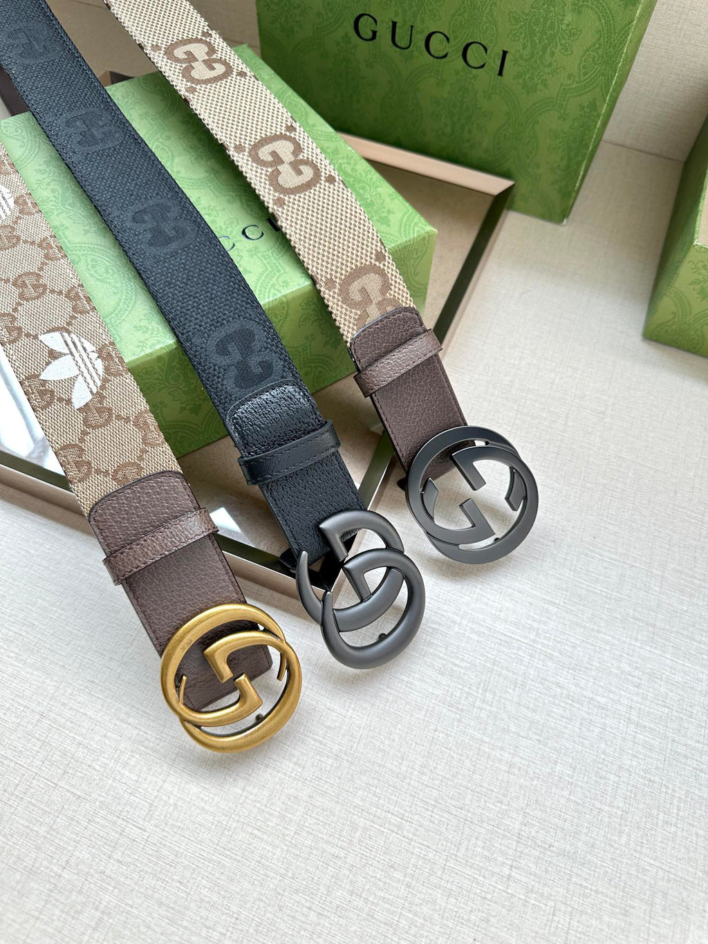 Gucci belts with GG logo buckles in silver and gold on dark leather straps