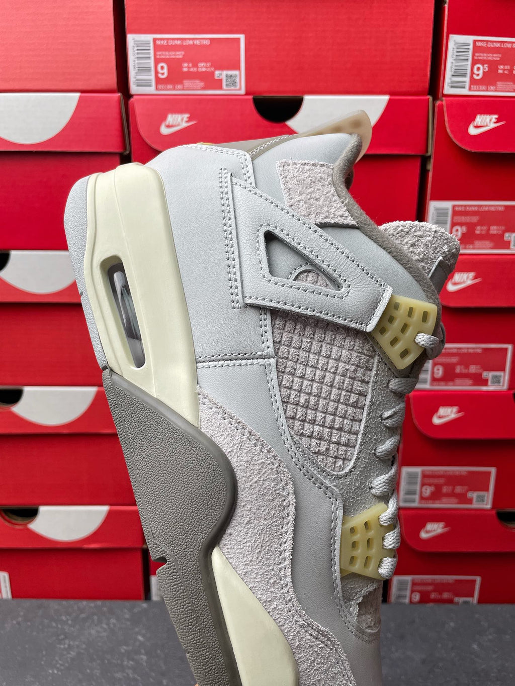 Light gray Air Jordan 4 sneaker heel and side with textured paneling, cream sole and yellow tabs