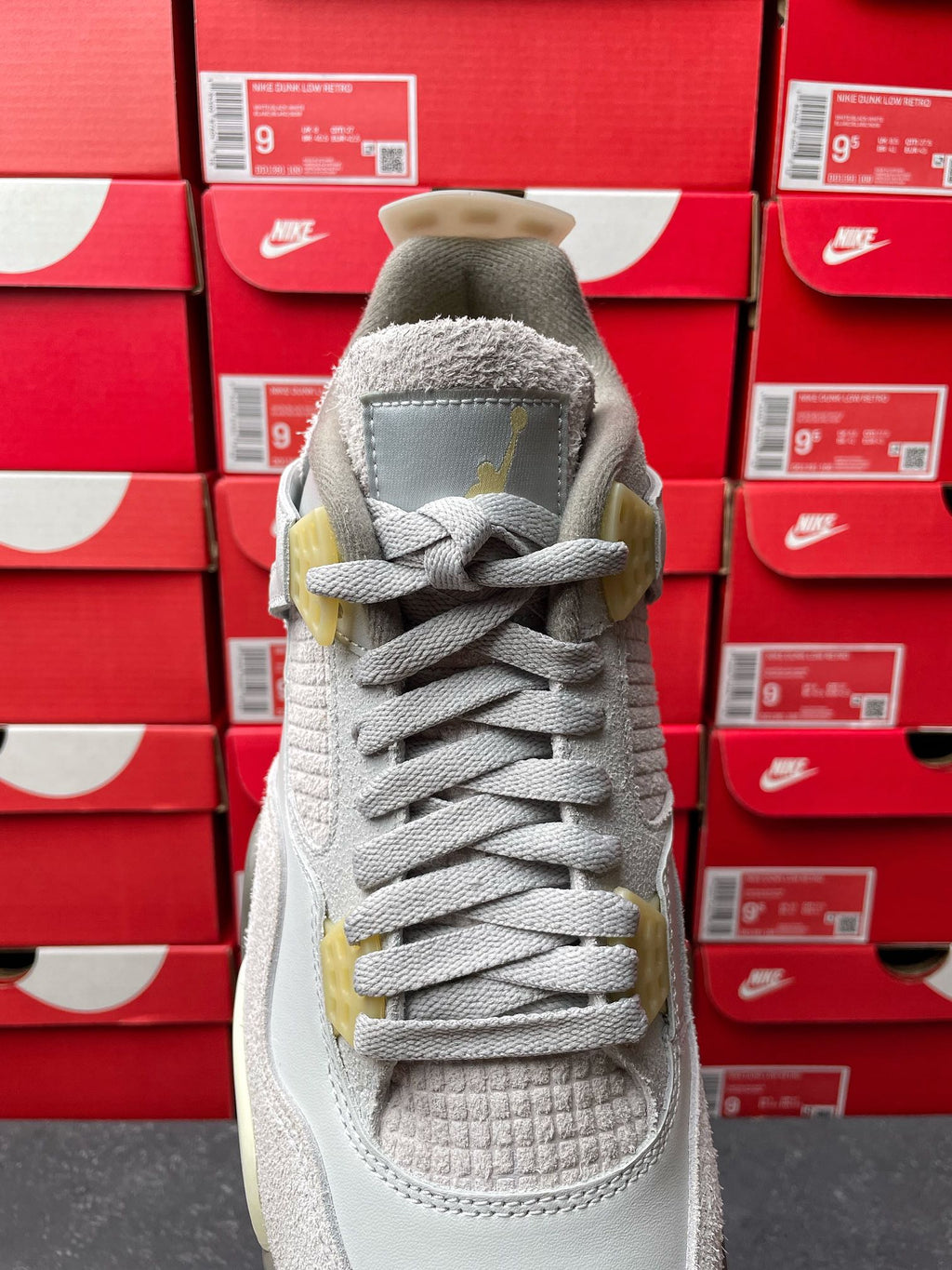 Light gray Air Jordan 4 sneaker top view with lace-up closure and textured collar